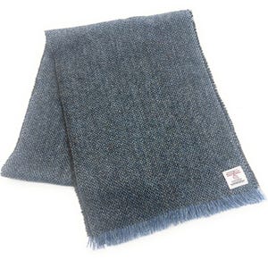 May include: A blue tweed scarf with a fringed edge. The scarf is made of a woven fabric with a textured appearance. A small white label with text is visible on the scarf.