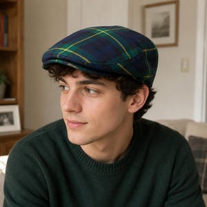 Puede incluir: Una gorra plana con un patrón de cuadros en azul oscuro y verde con finas líneas amarillas que se cruzan. La gorra tiene una copa redondeada y una visera corta y rígida en la parte delantera, confeccionada en tejido con textura visible.