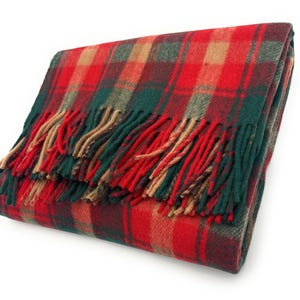 May include: Folded red, green, and tan plaid blanket with fringed edges. The blanket features a classic tartan pattern, with a mix of red, green, and tan squares. The fringed edges add a decorative touch to this cozy home textile.