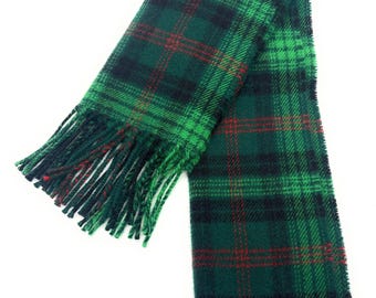 May include: A green and black plaid scarf with red accents and fringe. The scarf is made of a soft material and is designed in a classic tartan pattern. The fringe is a matching green color.