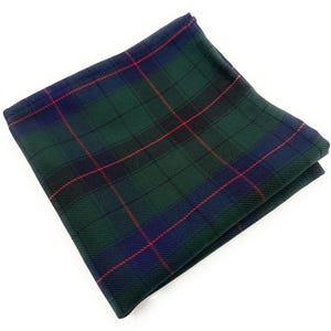 Può includere: Fazzoletto da taschino piegato con motivo scozzese verde, blu e rosso. Il tessuto presenta un classico motivo tartan, con linee intersecanti che creano un disegno a griglia. Il fazzoletto da taschino è piegato con cura, mostrando la simmetria e il contrasto cromatico.