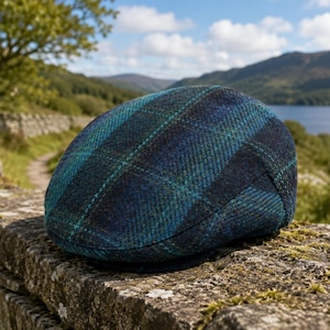 Puede incluir: Una gorra plana con un patrón de cuadros tejido en tonos azul marino profundo, verde bosque y verde azulado. La gorra tiene una copa redondeada y una visera corta y rígida en la parte delantera, hecha de tela de mezcla de lana texturizada.