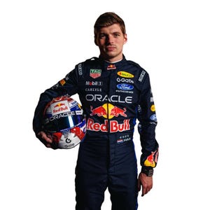 May include: A person wearing a dark blue racing suit and holding a Red Bull racing helmet. The helmet is white, red, and blue with the Oracle logo. The suit has sponsor logos including Oracle, Ford, and Red Bull.