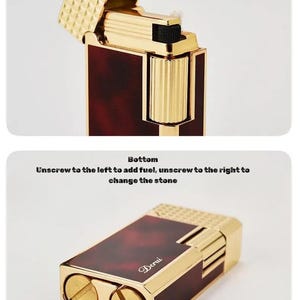May include: A gold and brown lighter with the lid open, revealing a textured gold surface. The lighter has a rectangular shape with rounded edges and the text "Handwheel with Smooth Damping" and "Excellent Feel and Easy to Play". The bottom has the text "Unscrew to the left to add fuel, unscrew to the right to change the stone".