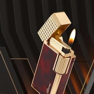 May include: A gold-colored lighter with a burgundy panel and a flame. The lighter is open, revealing its inner workings. The text "Derui" is visible on the lighter. The background is black with gold accents. The text "Noble, classic, and elegant Luxurious and mysterious" is also visible.