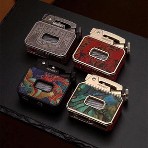 May include: Four square lighters with the word "HONEST" on each. The lighters have different designs: an Egyptian motif, a red marbled pattern, a colorful bird design, and a green and blue abalone shell pattern.
