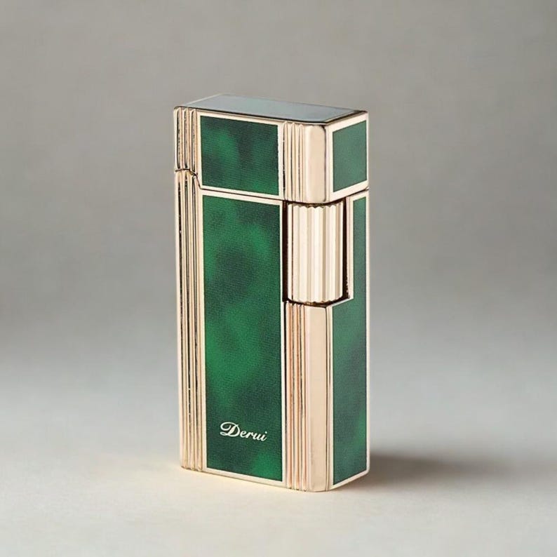 May include: A rectangular lighter with a gold-colored frame and a green marbled design. The lighter has a hinged lid and a textured, ribbed section. The word "Derui" is written in cursive on the front.