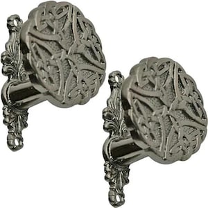 May include: Two antique-style, pewter-coloured curtain tiebacks. Each tieback features a round, ornate design with a Celtic knot pattern. The mounting hardware has a decorative, floral-like design.