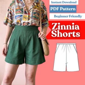 May include: A digital sewing pattern for Zinnia Shorts, featuring a graphic illustration of the shorts alongside text that reads Instant Download, PDF Pattern, Beginner Friendly, and Zinnia Shorts. The shorts are dark green with a high waist.