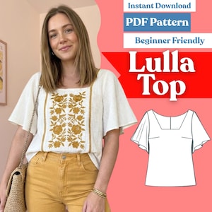 Puede incluir: Una blusa blanca con mangas cortas acampanadas y escote cuadrado, que presenta un panel central vertical de bordado floral color amarillo mostaza. Junto a la blusa hay un dibujo lineal en blanco y negro de la prenda etiquetada Lulla Top.