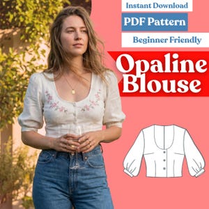 May include: A white blouse with short puff sleeves, a scoop neckline, and pink floral embroidery. The blouse features a front button closure and is paired with blue denim jeans. A line drawing of the blouse is shown alongside the text Opaline Blouse.