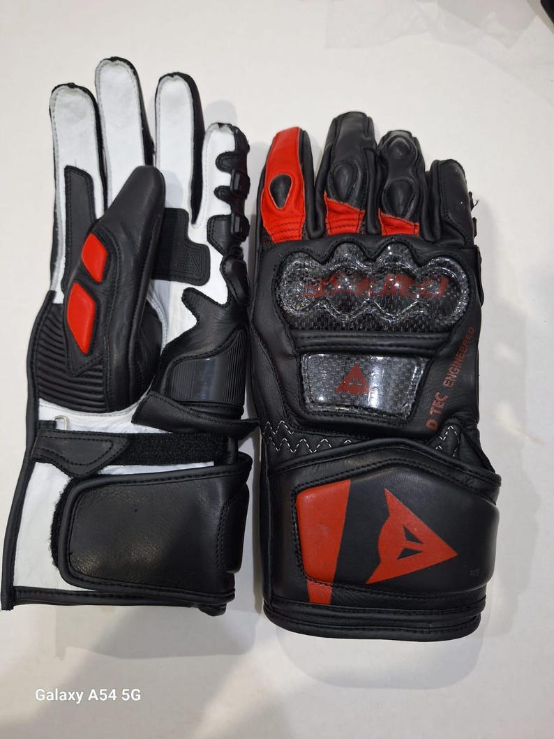 Pu&ograve; includere: Un paio di guanti da moto neri e bianchi con dettagli rossi. I guanti presentano un design protettivo per le nocche e il logo del marchio. I guanti sono in pelle e hanno una chiusura sicura al polso.