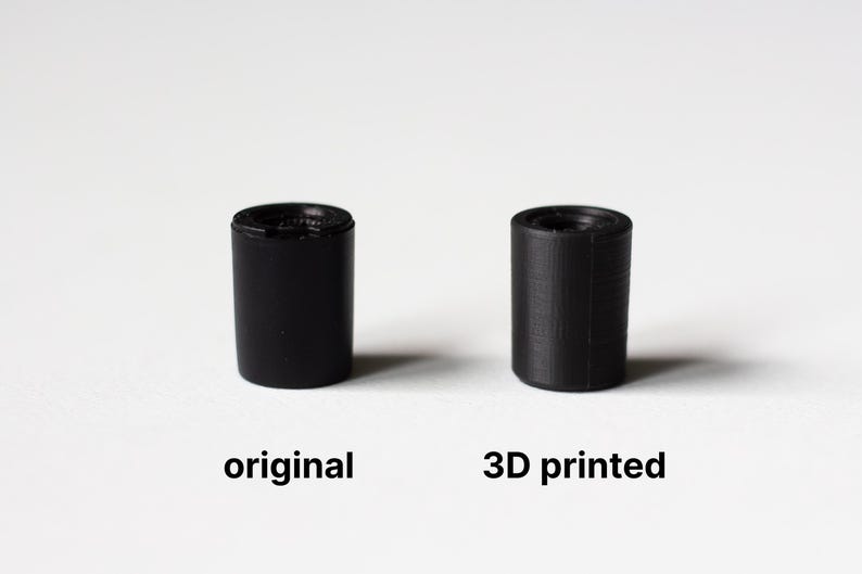 K&ouml;nnte beinhalten: Zwei schwarze zylindrische Objekte vor wei&szlig;em Hintergrund. Das linke Objekt ist mit "original" beschriftet, das rechte mit "3D printed". Die Objekte sind klein, m&ouml;glicherweise Komponenten oder Prototypen. Das Bild vergleicht die beiden.