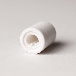 May include: A small, cylindrical white component with a hollow center and a visible internal notch. The exterior surface features fine, horizontal ridges consistent with 3D printing layers, creating a textured finish on the circular object.