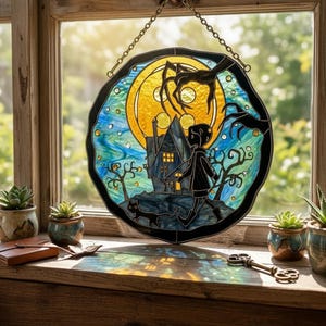 Puede incluir: Vidriera que representa una escena espeluznante con un ni&ntilde;o, un gato y una casa embrujada bajo la luna llena. La ventana es redonda con un borde negro y cuelga de una cadena. Los colores incluyen amarillo, azul y negro.
