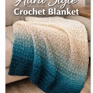 Op de afbeelding: Een gehaakte deken met een ombre-effect, die overgaat van crème naar teal. De deken is over een bank gedrapeerd. De tekst "Aura Style Crochet Blanket" staat bovenaan de afbeelding.
