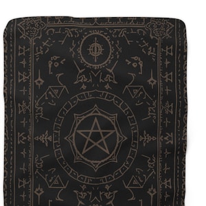 May include: Black throw blanket with a brown occult design. The blanket features a central pentagram, surrounded by circular patterns and symbols. The edges are lined with additional symbols, creating a mystical aesthetic.