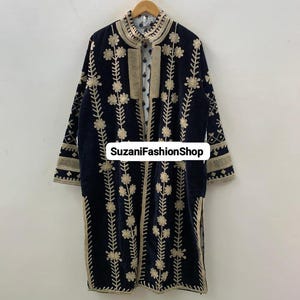 May include: A long, navy blue coat with detailed gold floral embroidery. The coat has a high collar and is displayed on a wooden hanger. The text "SuzaniFashionShop" is visible on the front of the coat.