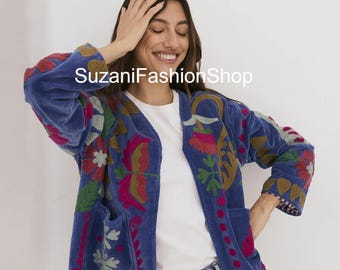 May include: A blue velvet jacket with colorful floral embroidery. The jacket has a relaxed fit, two front pockets, and three-quarter sleeves. The text "SuzaniFashionShop" is visible on the jacket.