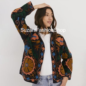May include: Black jacket with vibrant floral embroidery in orange, blue, and green. The jacket features a white lining and an open front. The text "SuzaniFashionShop" is visible on the jacket.