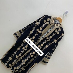 May include: A navy blue velvet coat with detailed gold floral embroidery. The coat has a high collar and gold trim on the edges and sleeves. The text "SuzaniFashionShop" is visible on the front.