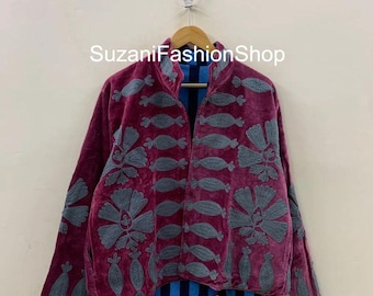 以下が含まれることがあります： グレーの刺繍の花柄と幾何学模様が施された、バーガンディ色のベルベットジャケット。 ジャケットはハイカラーで、前面が開いており、青と黒のストライプの裏地が見えます。 「SuzaniFashionShop」の文字が見えます。