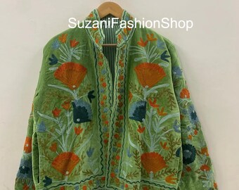 Op de afbeelding: Een groene fluwelen jas met ingewikkelde bloemenborduurwerk in oranje, blauw en groen. De jas heeft een opstaande kraag en een gestreepte voering. De tekst "Suzani FashionShop" is zichtbaar.