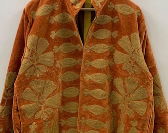 May include: An orange velvet jacket with intricate gold embroidery. The jacket features a mandarin collar and a reversible design with a yellow and brown striped lining. The floral and leaf-like embroidery adds a decorative touch to this garment.