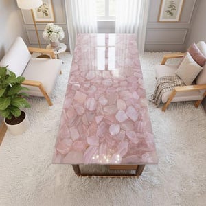 May include: A rectangular rose quartz table with a polished surface. The table is supported by a dark brown metal frame. The table's surface is made of irregular, light pink and white stones.