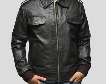 May include: A black leather jacket with a zip-up front, two chest pockets with button closures, and a collared neckline. The jacket has a brown ribbed cuff and hem. The person is wearing blue jeans.