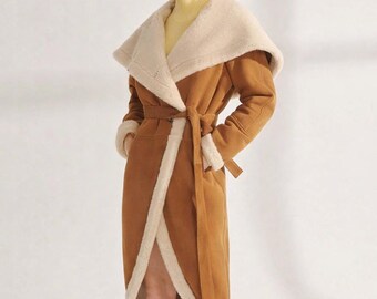 May include: A long, brown coat with a cream-colored, fluffy lining and collar. The coat has a wrap-around design with a matching belt. The sleeves and edges are trimmed with the cream-colored material. The coat is knee-length.