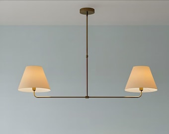 May include: A modern, two-light pendant lamp with a bronze finish. The lamp features two cream-colored, cone-shaped shades. The fixture is suspended from the ceiling by a central rod and horizontal arms.