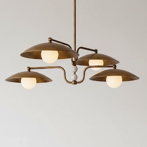 May include: A brass-toned chandelier with four lights. Each light has a round, white bulb and a curved, saucer-shaped shade. The fixture has a central stem and decorative white spheres.