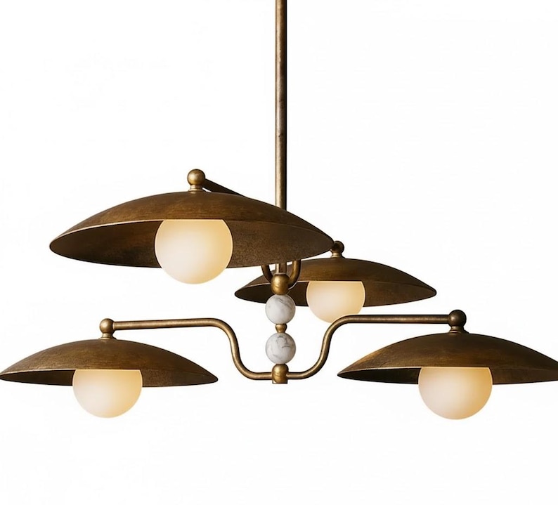 May include: A bronze-toned, multi-light chandelier with four downward-facing, saucer-shaped shades. Each shade has a spherical, frosted glass bulb. The fixture has a central stem and decorative marble accents.