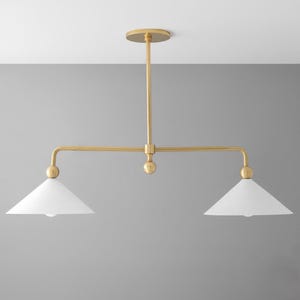 May include: A contemporary ceiling light fitting with a gold finish and two white, cone-shaped shades. The fixture features a horizontal bar with a light at each end and a central vertical support.