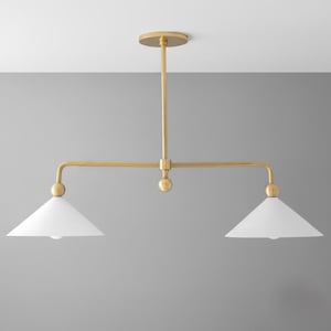 May include: A gold-coloured, two-light pendant light fitting with two white, cone-shaped shades. The fitting has a central stem and horizontal arms, with a circular ceiling mount.