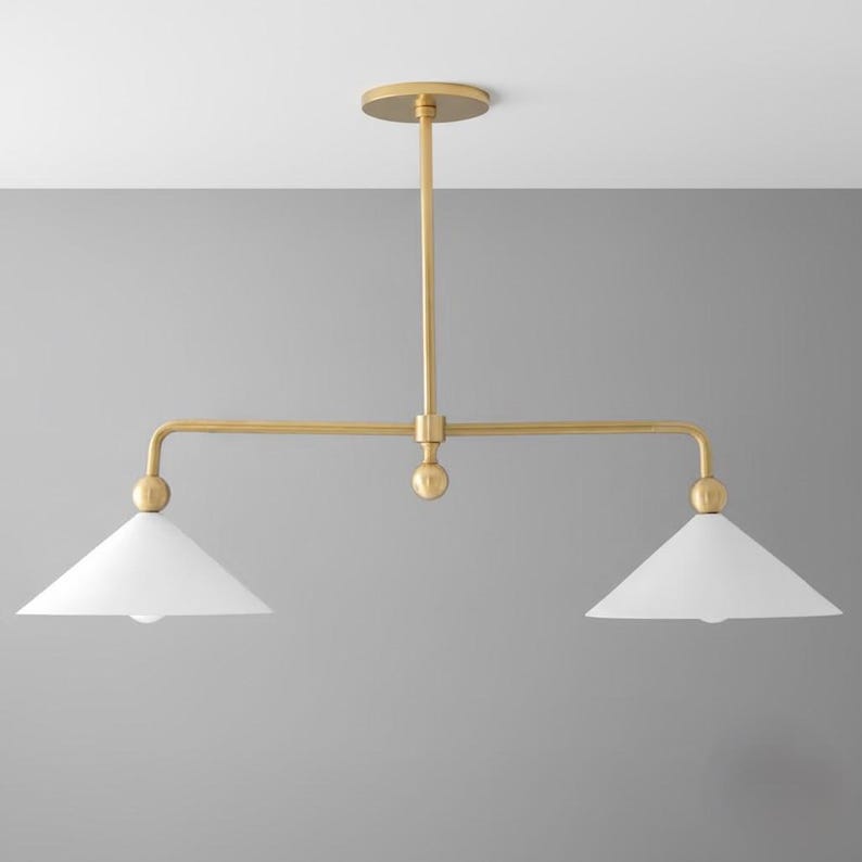 May include: A gold-coloured, two-light pendant light fitting with two white, cone-shaped shades. The fitting has a central stem and horizontal arms, with a circular ceiling mount.