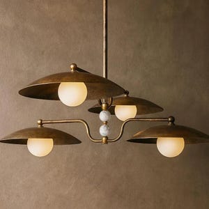 May include: A vintage-style chandelier with four lights. The fixture has a brass finish with saucer-shaped shades and spherical, frosted glass bulbs. The central support features decorative marble-like spheres.