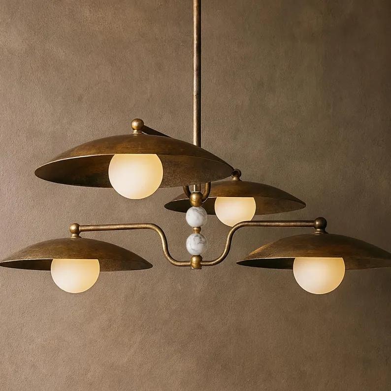 May include: A vintage-style chandelier with four lights. The fixture has a brass finish with saucer-shaped shades and spherical, frosted glass bulbs. The central support features decorative marble-like spheres.