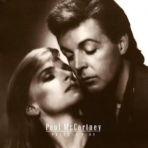 Könnte beinhalten: Sepiafarbenes Albumcover mit Paul McCartney und einer Frau in enger Umarmung. Der Text "Paul McCartney" und "PRESS TO PLAY" ist unten im Bild in Weiß dargestellt. Das Bild hat eine Vintage-Ästhetik.
