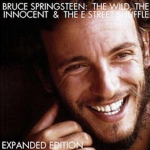 May include: Album cover for "Bruce Springsteen: The Wild, the Innocent & the E Street Shuffle - Expanded Edition." The image features a close-up of a smiling man with a beard. The album title and "Expanded Edition" are printed in white text.