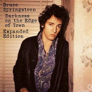 May include: Album cover for "Darkness on the Edge of Town: Expanded Edition" by Bruce Springsteen. The image features a man in a black leather jacket and a patterned shirt. The album title and artist name are printed in a bold, sans-serif font.