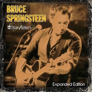 May include: Album cover for Bruce Springsteen's "Storytellers: Expanded Edition." The image features a sepia-toned photograph of Springsteen playing an acoustic guitar. The album title and artist name are in gold lettering.