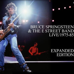 May include: Album cover for Bruce Springsteen & The E Street Band's "Live/1975-85" Expanded Edition. The image features Springsteen playing guitar on stage, with text reading "BRUCE SPRINGSTEEN & THE E STREET BAND LIVE/1975-85 EXPANDED EDITION" and "6CDs".