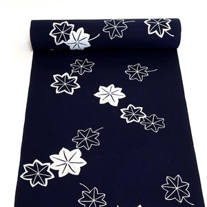 May include: A dark blue fabric with a white floral pattern. The fabric is rolled up and has a white background.