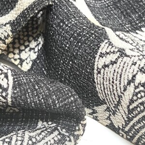 May include: Black and white patterned fabric with a textured surface. The fabric has a repeating pattern of abstract shapes.