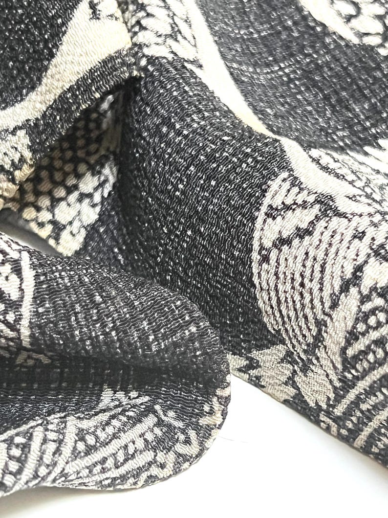 May include: Black and white patterned fabric with a textured surface. The fabric has a repeating pattern of abstract shapes.