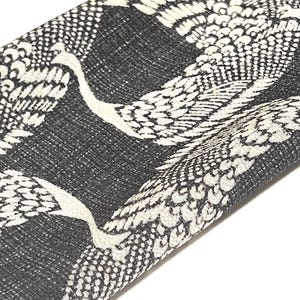 May include: Black fabric with a white crane pattern. The fabric is folded in half and the crane pattern is visible on both sides.