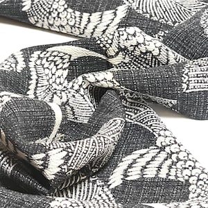 May include: Black and white fabric with a repeating pattern of stylized birds. The fabric has a textured surface.