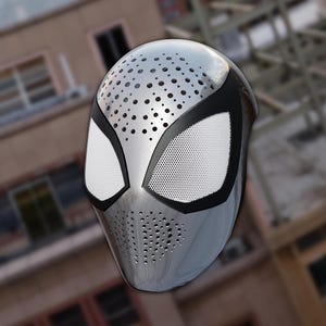 May include: A metallic silver full-face mask featuring a smooth, reflective surface with perforated holes across the forehead and chin areas. The mask includes two large, almond-shaped eye openings outlined in black with white mesh inserts.